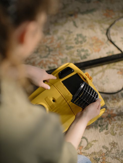 A person operating a portable yellow surface cleaning device, possibly a carpet cleaning or sanitising machine, on a traditional patterned rug with shades of beige, green, and orange. The device features a black grille and digital display, indicating it is used for deep cleaning or surface sanitisation at a residential location. The scene is well-lit, highlighting the cleanliness and neatness of the area, and the person appears focused on the task. This image exemplifies professional domestic cleaning services offered by error code: 521, aligning with surface cleaning and hygiene procedures described on the page about emergency carpet cleaning same day in N1, common problems, N1.